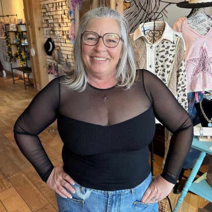 The Sheer Aura sweetheart top in black, paired with denim for an elevated casual look.